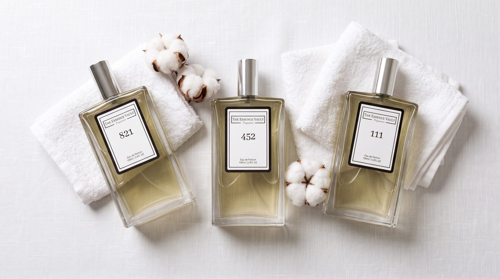 Three TEV perfume bottles - No. 821, No. 452, No. 111 - on white linen with cotton blossoms and soft morning light