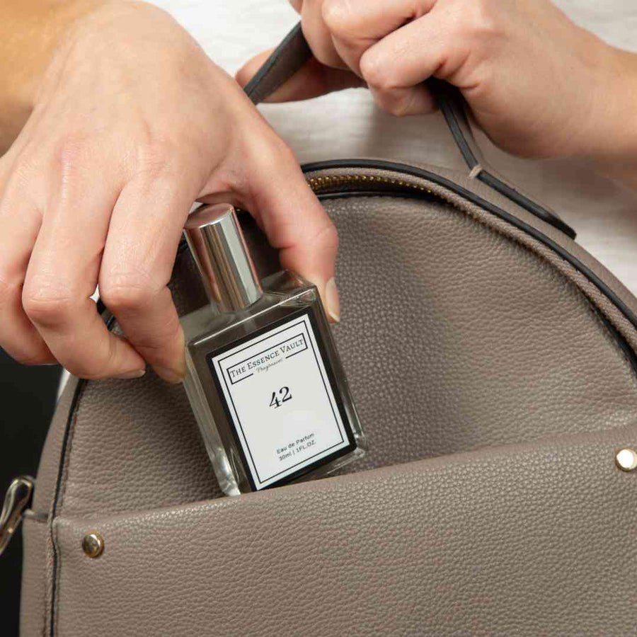 The Essence Vault image of someone putting a perfume in their bag, for the blog post Your Guide to Travel Fragrance this Summer