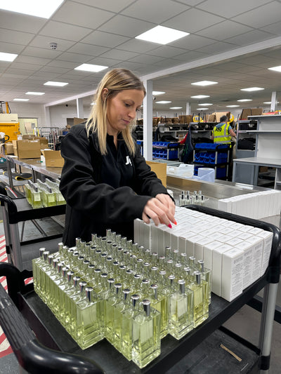 Person in a warehouse setting with shelves and perfume bottles.
